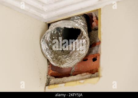 Vecchio condotto di ventilazione in alluminio flessibile con polvere in primo piano. Guasto del sistema di ventilazione nella stanza Foto Stock