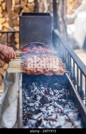 Pezzi di carne storti su spiedini di metallo sulla griglia al tramonto Foto Stock