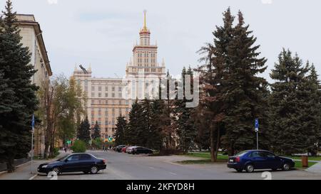 La strada e le automobili e un gran numero di abeti di fronte alla South Ural state University Foto Stock