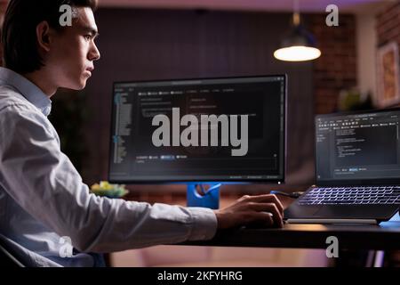 Sviluppatore di software che codifica il programma firewall sul monitor e sul laptop, utilizzando il server di crittografia per script di rete di sicurezza con codice binario. Sviluppo di app su interfaccia di testo dati, programmazione IT. Foto Stock