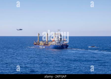 221015-N-FD648-1080 IONIAN SEA (15 ottobre 2022) un elicottero MH-60R Sea Hawk, attaccato ad Helicopter Maritime Strike Squadron (HSM) 46, e una barca gonfiabile a scafo rigido, attaccata al cacciatorpediniere di missili guidati di classe Arleigh Burke USS Farragut (DDG 99), si avvicinano ad una nave per una visita, consiglio, ricerca, E l'esercizio di sequestro durante l'attività di vigilanza condotta dalla NATO Nettuno Strike 22,2 (NEST 22,2), 15 ottobre 2022. Carrier Air Wing (CVW) 7 è la componente offensiva di Carrier Strike Group 10, George H.W. Gruppo di riscontro supporto boccola (GHWBCSG). Gli squadroni del CVW-7 sono Squa Strike Fighter Foto Stock