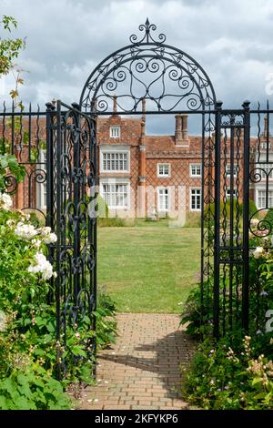 Estate Ritratto vista di metallo ornato gateway a confini erbacei in Helmingham Hall e Giardini Suffolk Foto Stock