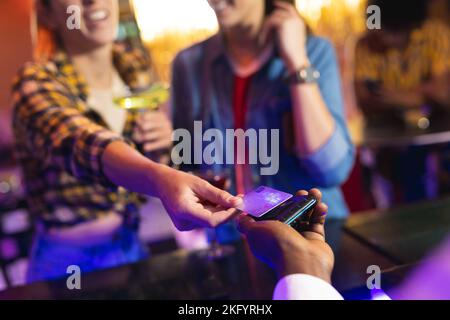 A metà strada tra barman e donna che pagano bevande con carta di credito al bar Foto Stock