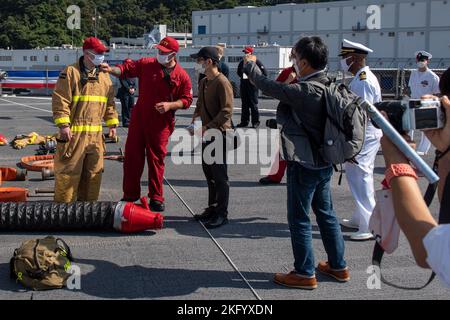 YOKOSUKA, Giappone (ott 16, 2022) – Damage Controlman 1st Class Brandon Carrick (tute rosse) spiega le funzioni di un ensemble antincendio per i membri della stampa giapponese durante un tour a bordo della nave ammiraglia US 7th Fleet USS Blue Ridge (LCC 19) Come parte delle attività della flotta del comandante Yokosuka la prima festa dell’amicizia dall’inizio della pandemia COVID 19. L'evento a base aperta mette in evidenza la partnership tra la Marina degli Stati Uniti e la nazione ospitante del Giappone. Blue Ridge è la più antica nave operativa della Marina e, come 7th Fleet Command ship, lavora attivamente per promuovere le relazioni con Foto Stock