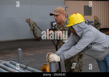 221018-N-N0874-1089 NORFOLK, Virginia (ott 18, 2022) Logistic Specialist 2nd Classe Manuel Miguel, a sinistra, da Fresno, California, e Barry Kelly, Da Chesapeake, Virginia, un appaltatore per Norfolk Naval Shipyard, spostare il carico a bordo della portaerei di classe Nimitz USS Harry S. Truman (CVN 75), 18 ottobre 2022. Truman è la nave ammiraglia del gruppo di carrier Strike di Harry S. Truman ed è attualmente in porto presso la Naval Station Norfolk. Foto Stock