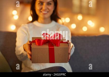 Donna felice sorridendo e tenendo fuori una scatola bella con un regalo magico di Natale Foto Stock