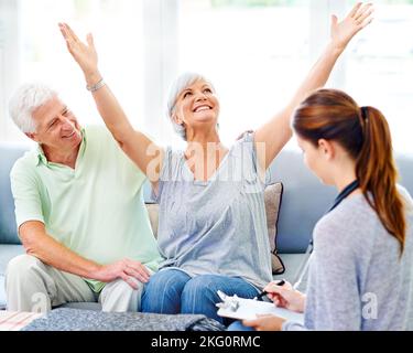 Si è rallegrato dei risultati dei suoi test. Un medico che spiega i risultati positivi del test ad un paziente anziano molto felice e a suo marito. Foto Stock