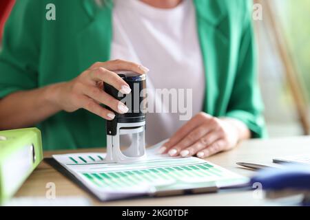 Mano femmina che tiene in mano i documenti statistici di bollo in gomma e stampaggio Foto Stock