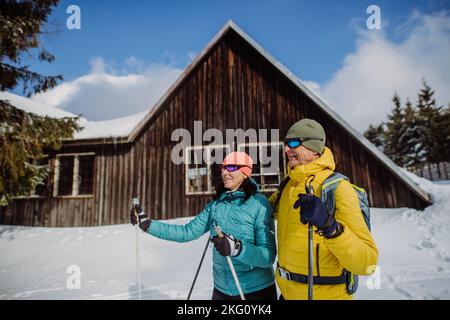 Coppia anziana in pausa durante lo sci, prossimo cottage foresta. Foto Stock