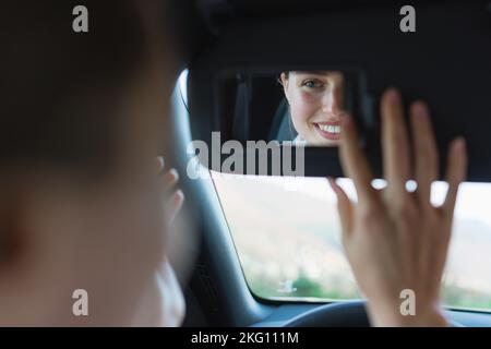 Vista posteriore della giovane donna in auto, guardando lo specchietto retrovisore. Foto Stock