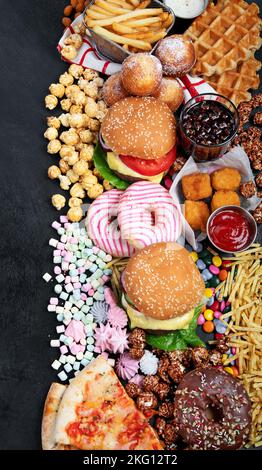 Prodotti malsani. Cibo cattivo per figura, pelle, cuore e denti. Assortimento di alimenti a base di carboidrati veloci con patatine fritte e cola su sfondo scuro. Top vi Foto Stock