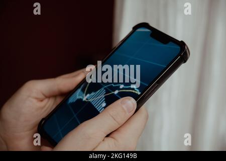 Mani femminili che tengono il telefono, controllando il grafico del mercato azionario per il tranding e l'investimento nel cambio di sicurezza. Donna in attesa di telefono Visualizza la schermata dell'indice delle azioni. Concetto di investimento di mercato azionario contabilità Finanza Foto Stock