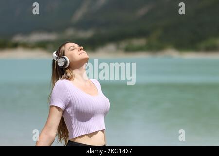 Donna che indossa cuffie meditando nella natura ascoltando l'audio Foto Stock