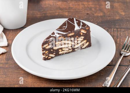 Torta di mosaico al cioccolato su un piatto di porcellana bianca con caffè filtro sul lato Foto Stock
