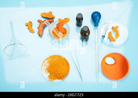 Ricerca medica delle proprietà curcuma con l'aiuto di attrezzature di laboratorio, donna in guanti di prova curcuma polvere. Vista dall'alto. Foto Stock