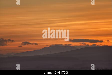Tramonto invernale con lontano parco eolico, Scozia Foto Stock