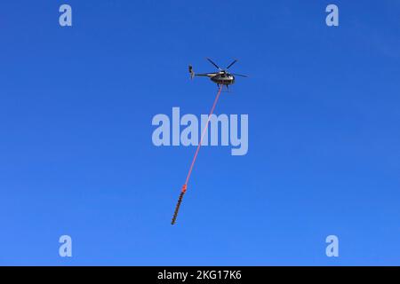 Elicottero Heliwest e sega aerea per tagliare alberi da linee elettriche contro il cielo blu. Spazio di copia. Salo, Finlandia. Febbraio 10, 2022. Foto Stock