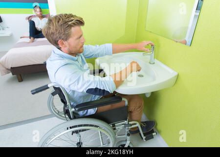 uomo portatore di handicap che usa il bagno in camera Foto Stock