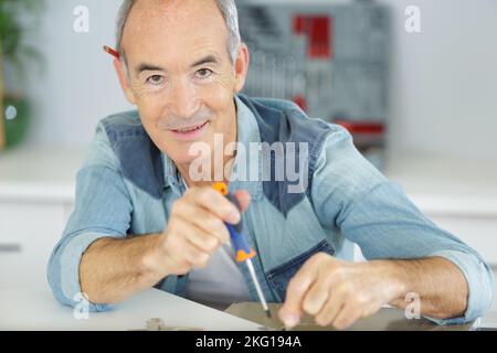 avvitamento senior di una maniglia sul lato del cassetto Foto Stock
