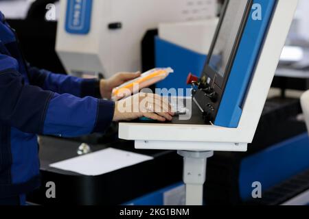 Operatore alla console di controllo della macchina da taglio laser CNC. Messa a fuoco selettiva. Foto Stock