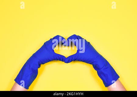 Le mani di lavoro in guanti protettivi in gomma mostrano il cuore. Foto Stock
