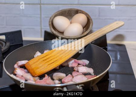 Pancetta fritta in una padella come la base di buone uova strapazzate. Foto Stock