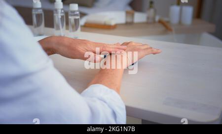 Bellezza femminile procedure salute concetto di cura della pelle. Primo piano irriconoscibile vecchio anziano maturo di mezza età rugosa donna strofinando le mani applicando naturale Foto Stock