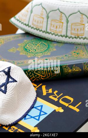 Simboli religiosi : cappello musulmano di Kufi con il Corano, e Kippah ebraico con la Torah. Concetto di dialogo interreligioso o interreligioso. Foto Stock