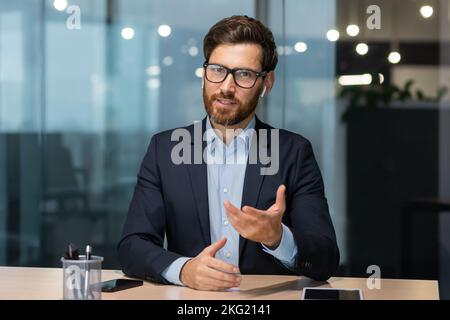 Visualizzazione videochiamata con webcam, boss maturo felice che parla con i colleghi in remoto, uomo che guarda la videocamera seduto in ufficio, investitore in una riunione online con i partner amichevole sorridendo e chattando. Foto Stock