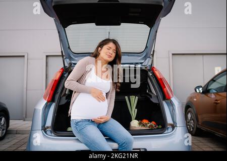 Futura madre sensazione di dolore nella pancia addominale durante lo shopping di maternità. Foto Stock