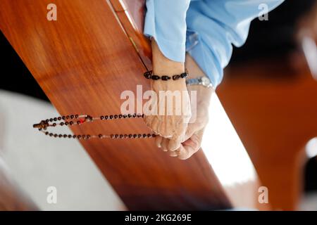 Suora dominicana che paga le perle del rosario. Primo piano sulle mani. Chiesa cattolica. Bien Hoa. Vietnam. Foto Stock