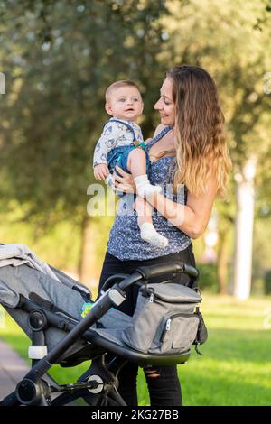 Madre e suo figlio nel parco con il passeggino Foto Stock