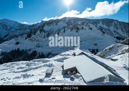 Fuco di alba invernale con i raggi del sole sopra la cresta con rifugio di montagna Foto Stock