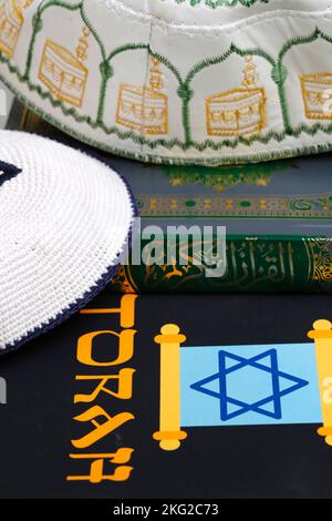 Simboli religiosi : cappello musulmano di Kufi con il Corano, e Kippah ebraico con la Torah. Concetto di dialogo interreligioso o interreligioso. Foto Stock