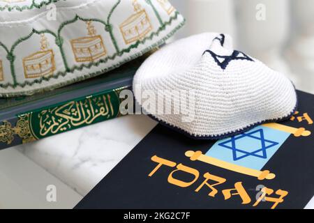 Simboli religiosi : cappello musulmano di Kufi con il Corano, e Kippah ebraico con la Torah. Concetto di dialogo interreligioso o interreligioso. Foto Stock