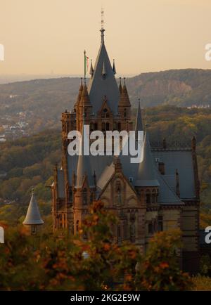 Uno scatto verticale del castello di Drachenburg circondato da alberi colorati in autunno Foto Stock