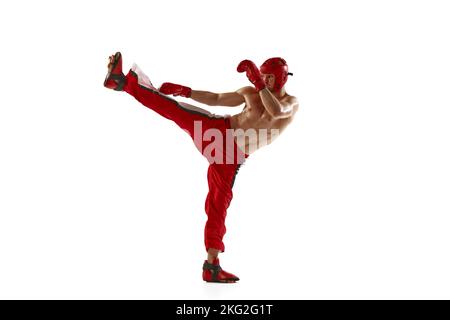 Giovane kickboxer professionista che indossa casco e guanti da boxe in movimento isolati su sfondo bianco. Sport, competizione, energia, sport di combattimento Foto Stock