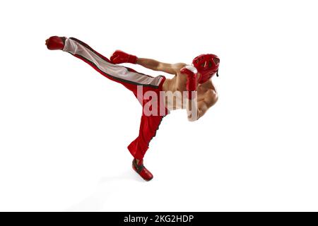 Giovane kickboxer professionista che indossa casco e guanti da boxe in movimento isolati su sfondo bianco. Sport, competizione, energia, sport di combattimento Foto Stock