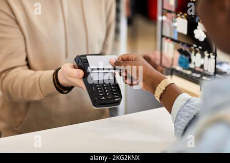 Primo piano della cliente femminile che paga in negozio di abbigliamento tramite carta di credito, spazio copia Foto Stock