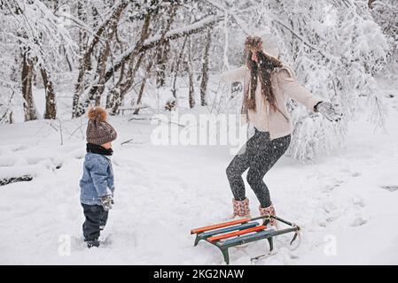 Mamma e figlio camminano nella neve nella foresta invernale. Foto Stock