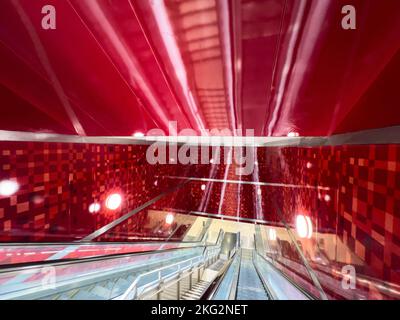 All'interno di una stazione della metropolitana. Una lunga scala mobile si sposta in profondità nel design interno delle pareti di colore rosso. Foto Stock