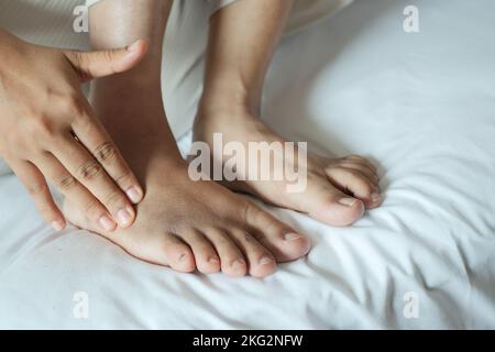 giovani donne che soffrono dolore ai piedi seduti a letto Foto Stock