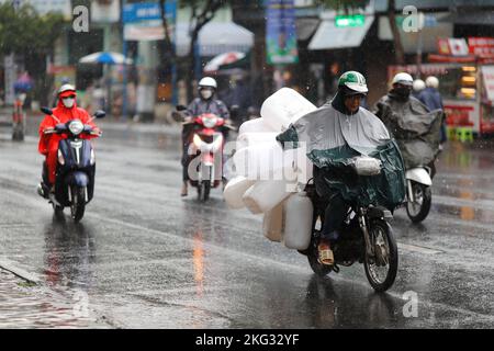 I vietnamiti indossano casco e impermeabile in moto con forte pioggia, acqua sulla strada. Stagione delle piogge a Saigon, città di ho Chi Minh. Vietnam. Foto Stock