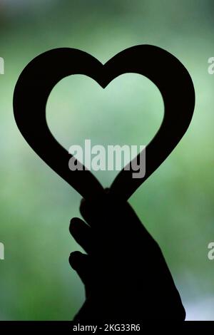 Donna che tiene un cuore di legno. Primo piano a portata di mano. Concetto di amore. Foto Stock