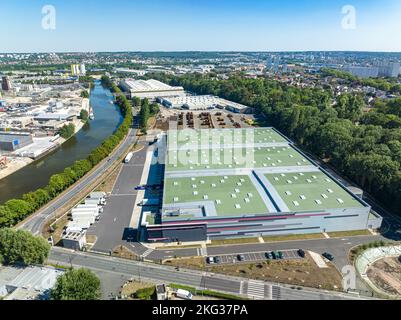 Drone shot di zona industriale con lago nel mezzo di molte infrastrutture commerciali e verde lussureggiante a Bonneuil sur Marne, Francia Foto Stock