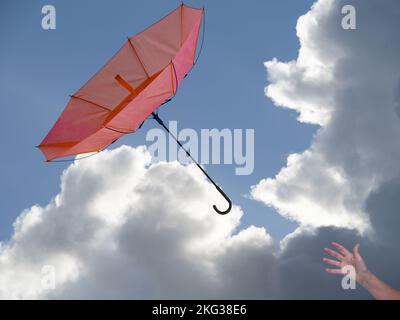 Mano della donna con dentro fuori ombrello in busto di vento, cielo dietro. Foto Stock