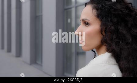 Primo piano vista posteriore Caucasian pensiva signora di brunette premurosa con i capelli lunghi ricci che guardano via pensando sognando meditando pensare in piedi Foto Stock