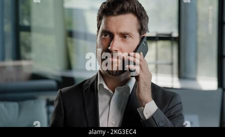 Ritratto barbuto caucasico uomo d'affari adulto di mezza età che parla telefono in ufficio negoziare la conversazione di vendita virtuale utilizzando il professionista mobile maschio Foto Stock