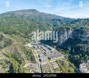 Veduta aerea del terreno tropicale coperto da foreste a rischio di estinzione e vari edifici commerciali nelle Alpi Marittime, Francia Foto Stock