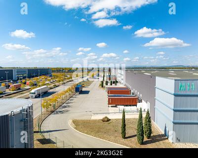 Foto drone dell'area esterna del magazzino circondata da veicoli caricati con inventario e parcheggiata in fila Foto Stock